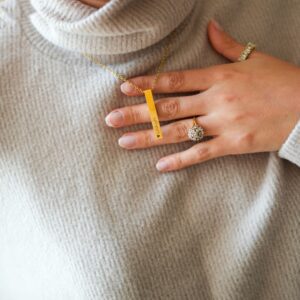 Mannequin portant un collier avec une barre contenant gravure, exposé sur sa main