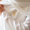 Mannequin vétu en blanc, portant un bijou personnalisé - collier tressé et son disque gravé
