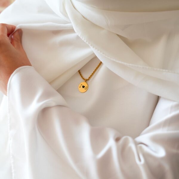 Mannequin vétu en blanc, portant un bijou personnalisé - collier tressé et son disque gravé