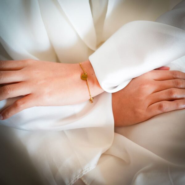 bras croisés, le mannequin vétu en blanc jusqu'au poignet exibe un bracelet personnalisé