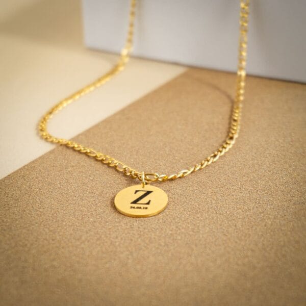 Zoom sur un pendentif doré gravé avec la lettre Z et une date