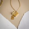 chaine avec une lettre en pendentif contenant une plaque gravé d'un message d'amour