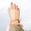 Main au ciel portant une bague et un bracelet dorés, Teman