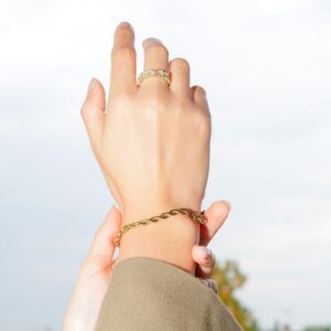 Main au ciel portant une bague et un bracelet dorés, Teman