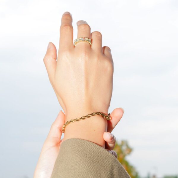 Main au ciel portant une bague et un bracelet dorés, Teman