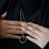 lot de deux collier dorés tenu à deux mains, vêtement voile noir