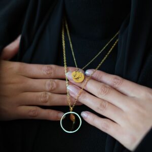 lot de deux collier dorés tenu à deux mains, vêtement voile noir