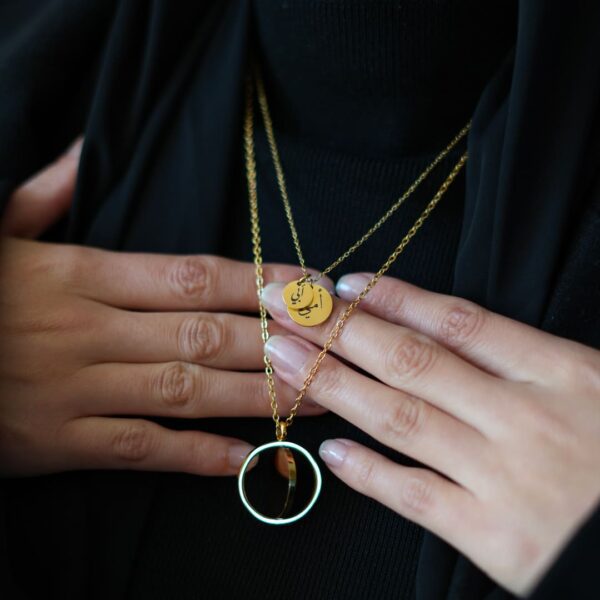 lot de deux collier dorés tenu à deux mains, vêtement voile noir