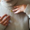 Bijou doré et son pendentif personnalisé porté au cou sur pull en laine
