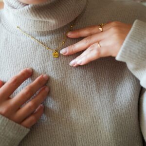 Bijou doré et son pendentif personnalisé porté au cou sur pull en laine
