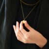 Collier Ummi gravé sur un petit disque, porté et tenu à une main