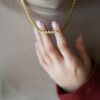 Collier doré torsadé porté au cou, tenu en main