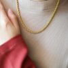 Collier doré torsadé porté au cou