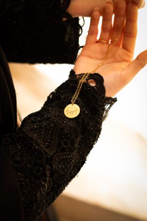 Collier personnalisé, gravé avec le dessin d'un famille fait par un enfant, tenu en main