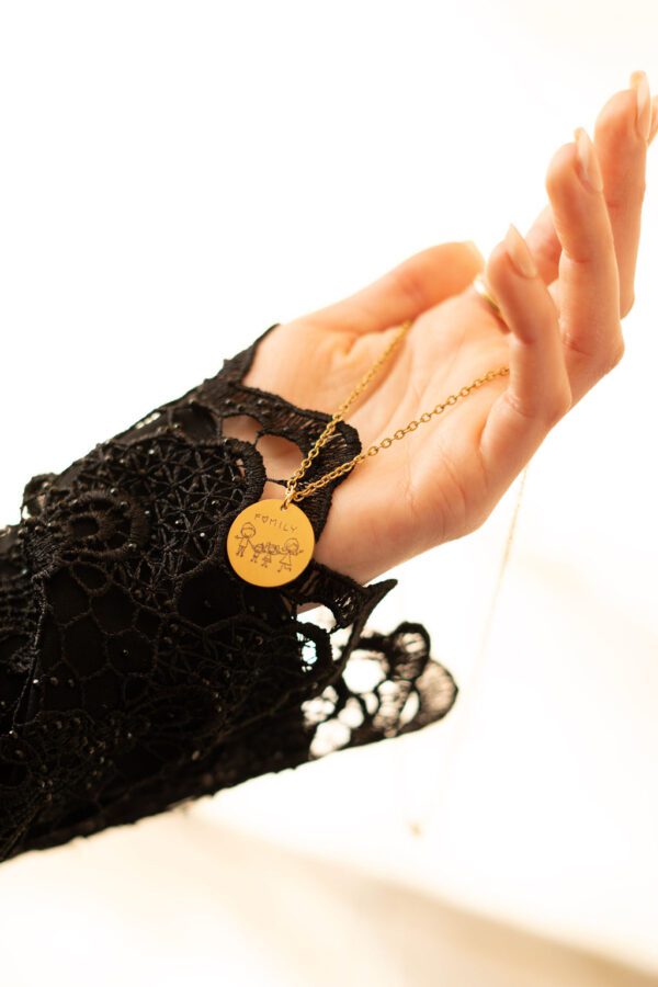 Collier personnalisé, gravé avec le dessin d'un famille fait par un enfant, tenu en main